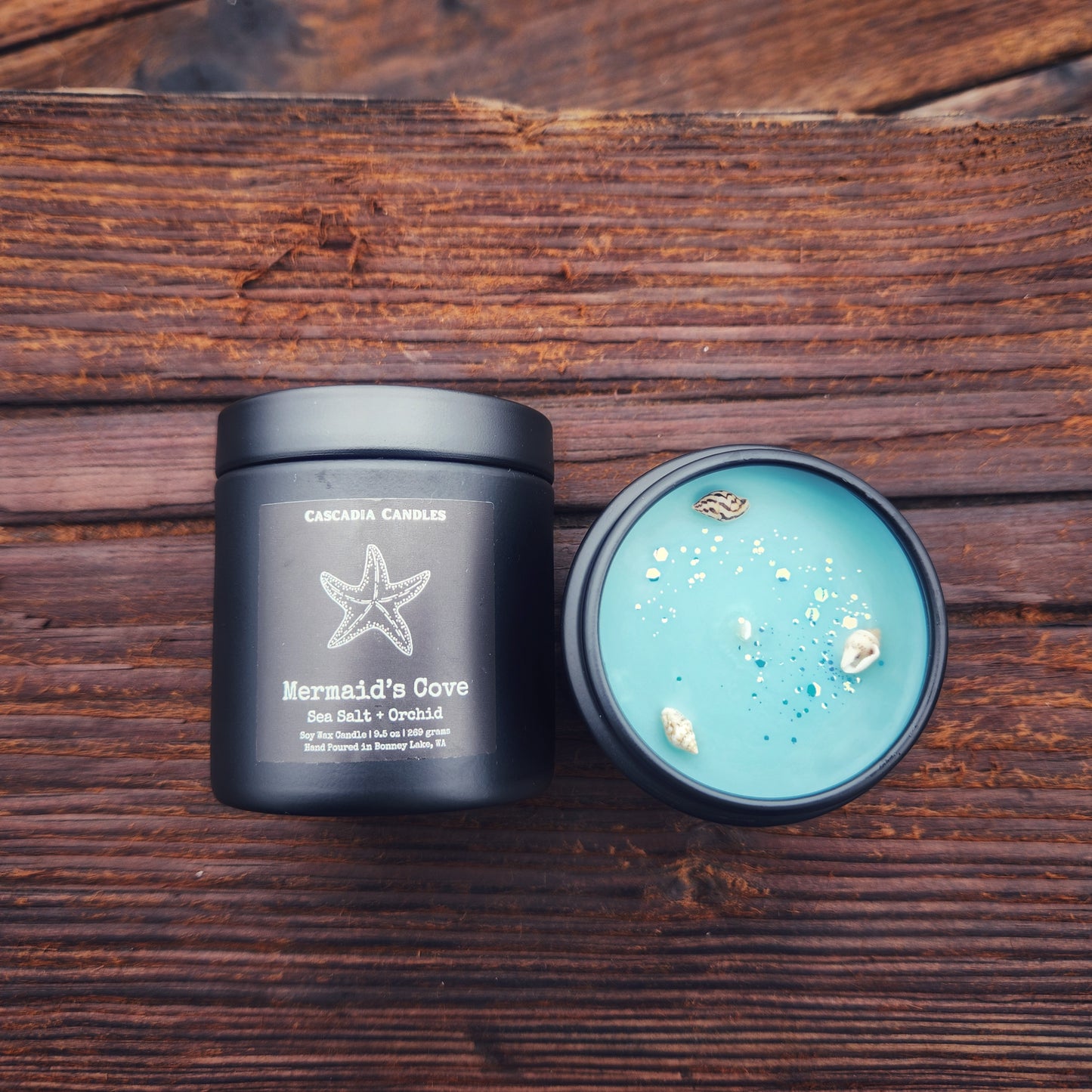 Top and front view of 'Mermaid's Cove' candle pictured on a wood beam.
