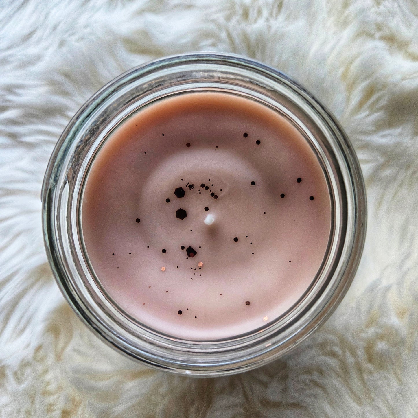 Top view of Witch's Brew candle on a white fluffy surface, showing the glitter on top.