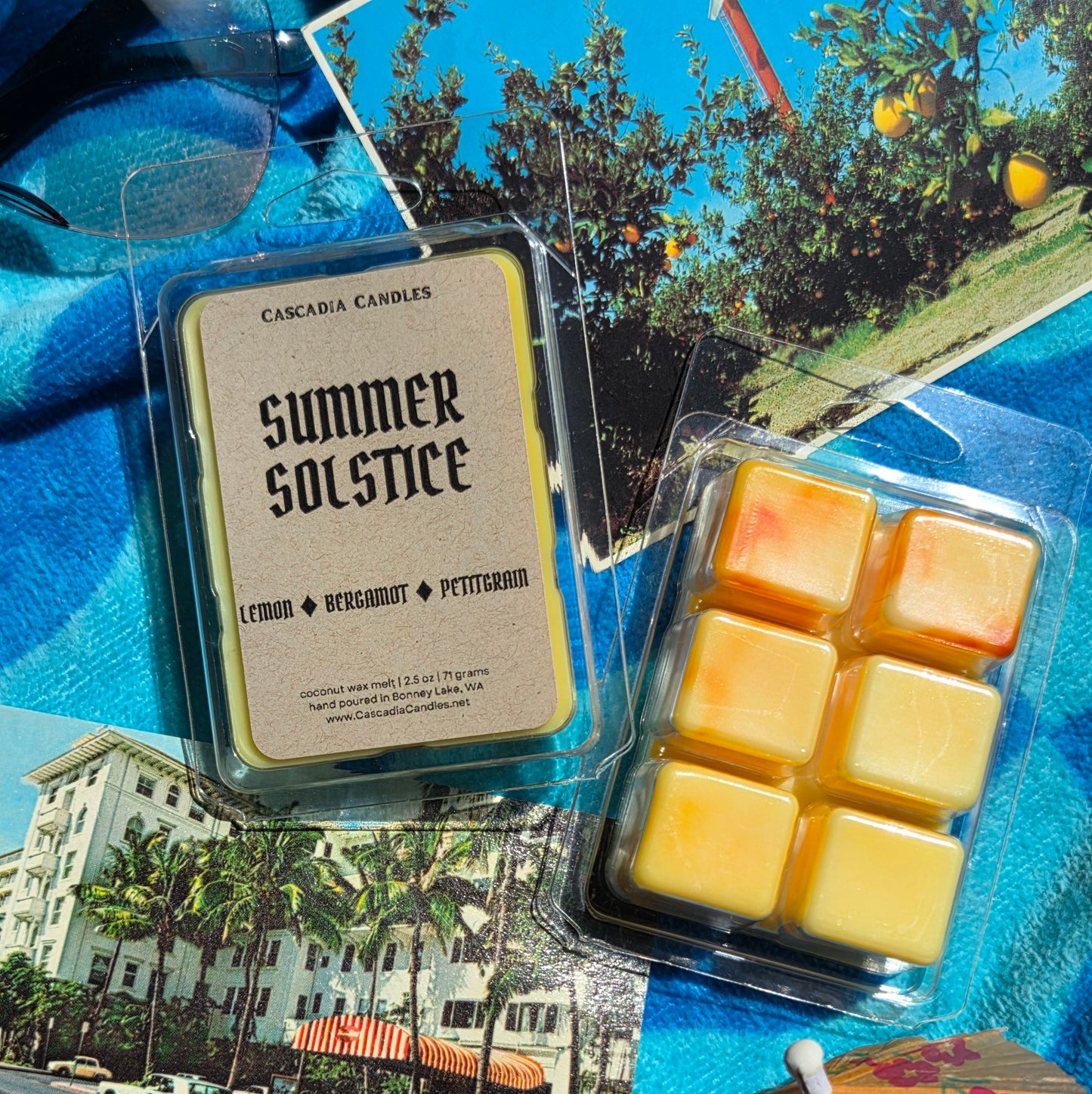 Packaged wax melts labeled 'Summer Solstice' with a scenic background.