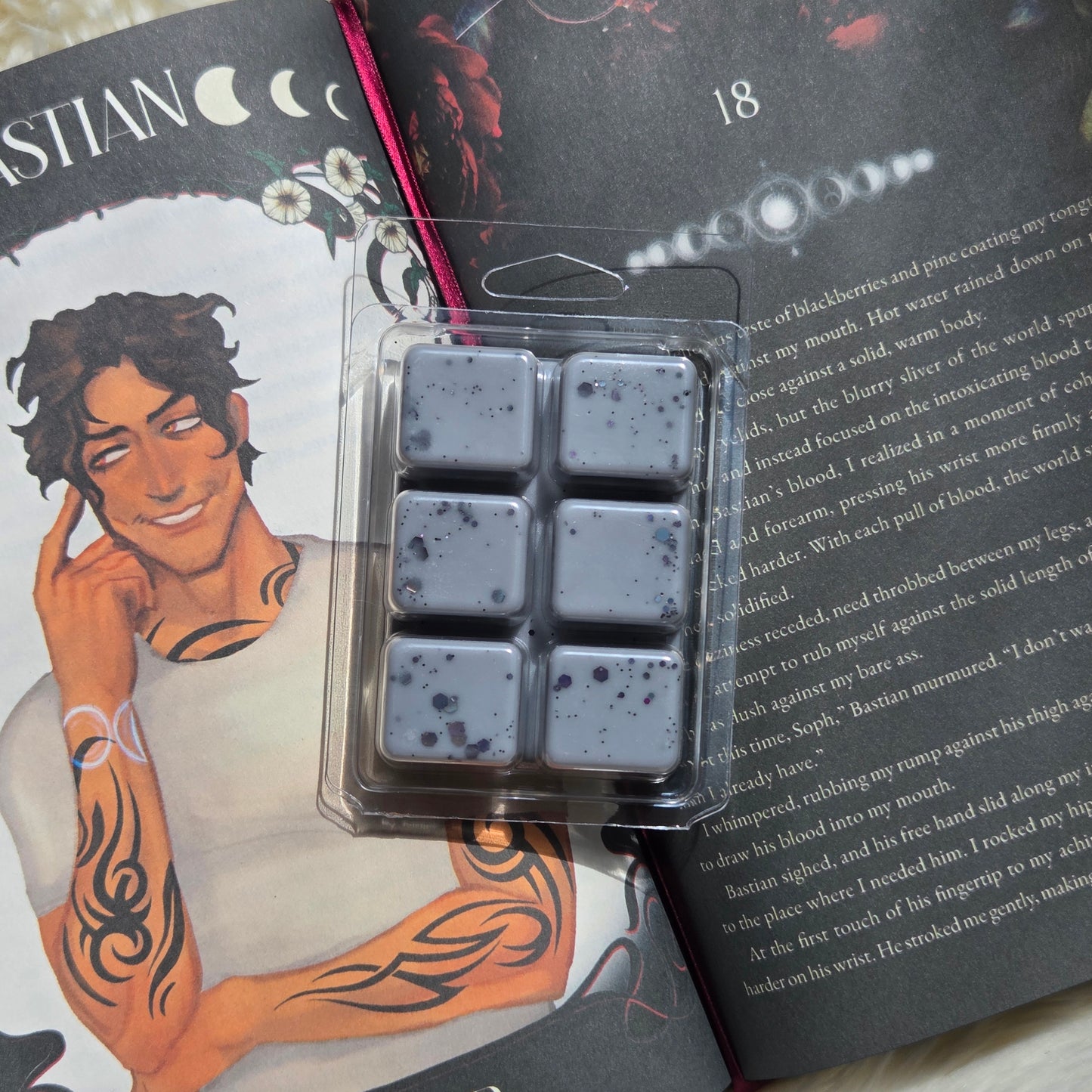 Six square wax melts in a clear plastic clamshell package, arranged in a 2x3 grid. The wax is a muted grayish purple with dark speckles.