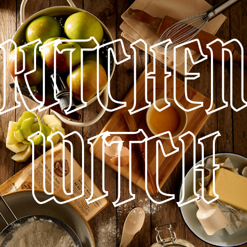 A rustic kitchen scene with ingredients and baking tools arranged on a wooden table, overlaid with large white outlined text reading 'KITCHEN WITCH'. Visible items include green apples, flour, eggs, butter, a whisk, a mug of liquid, and napkins.