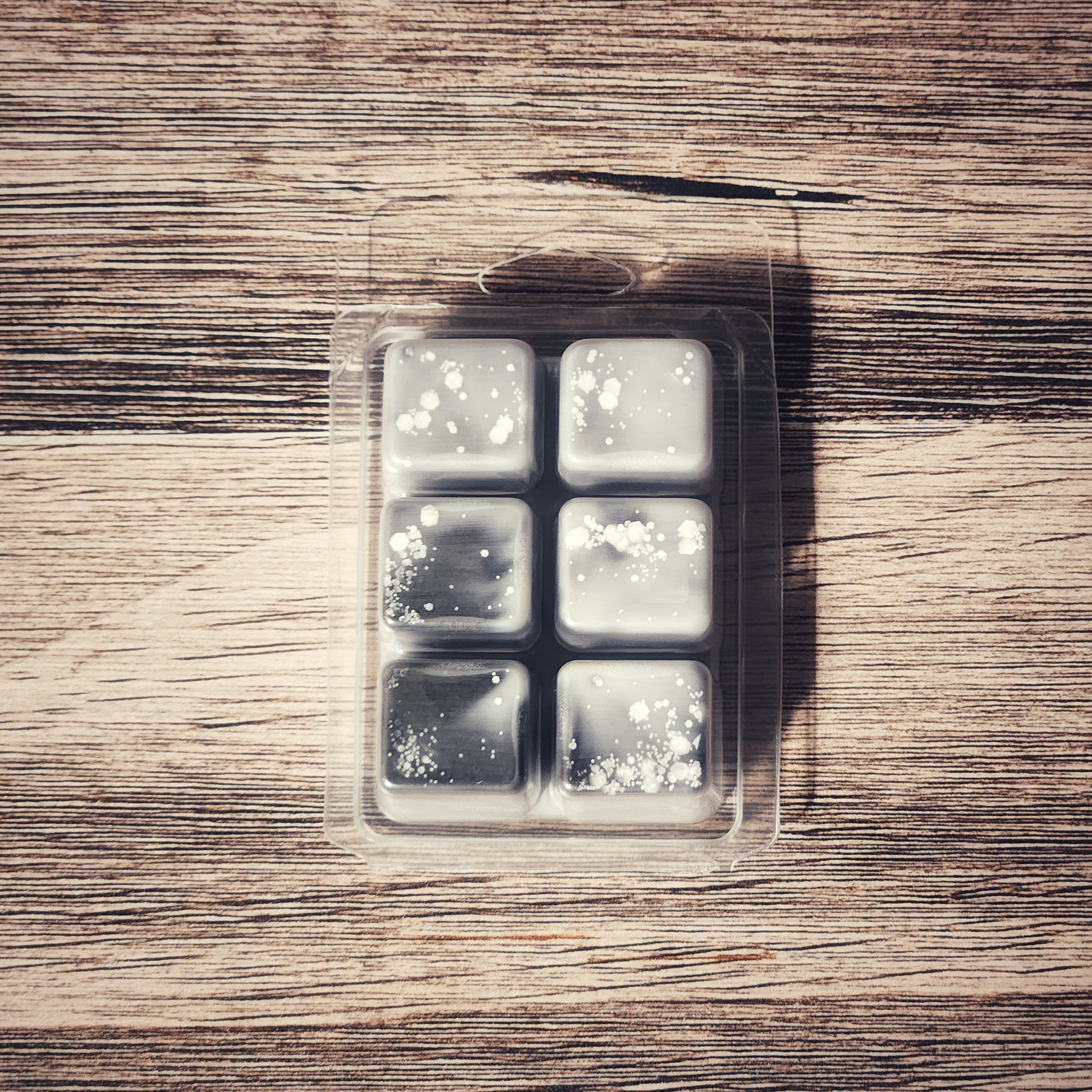 Pack of six wax melts in a clear plastic packaging on a wooden surface