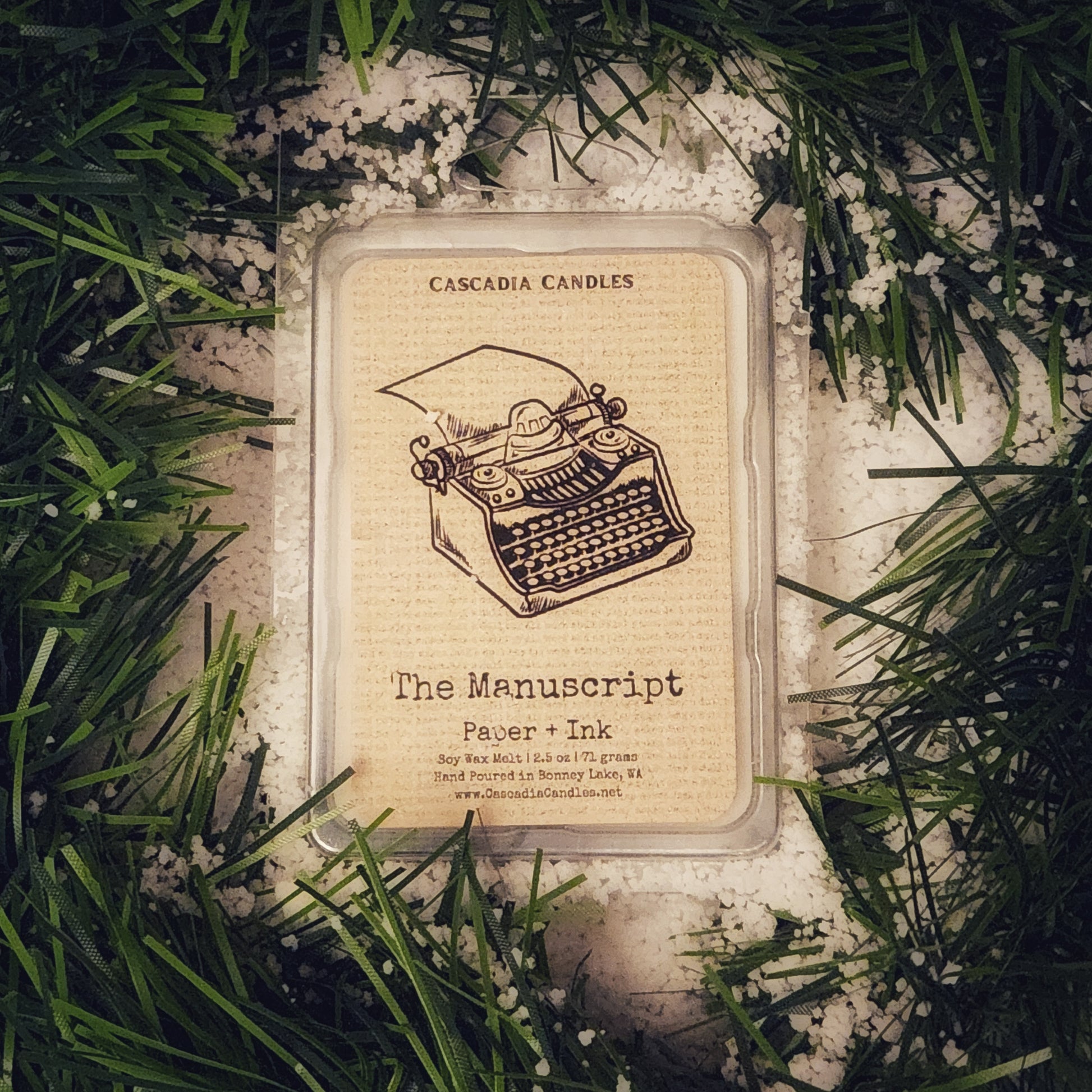 Cascadia Candles product packaging with typewriter illustration on a snowy garland background