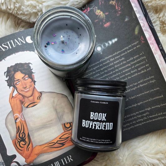 Candle labeled 'Book Boyfriend' with a book and illustration of a man on a surface