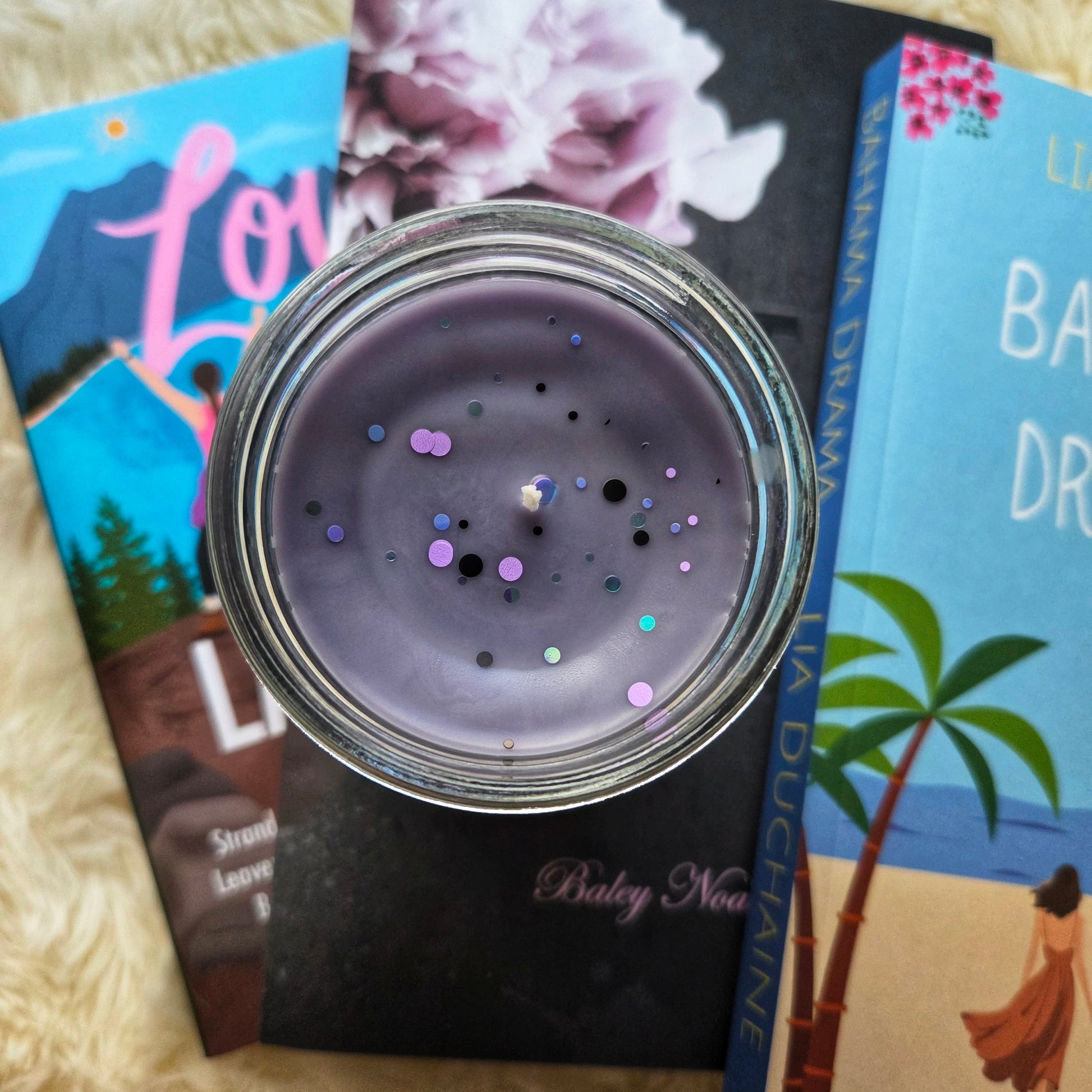 Candle jar with glitter on top, surrounded by books