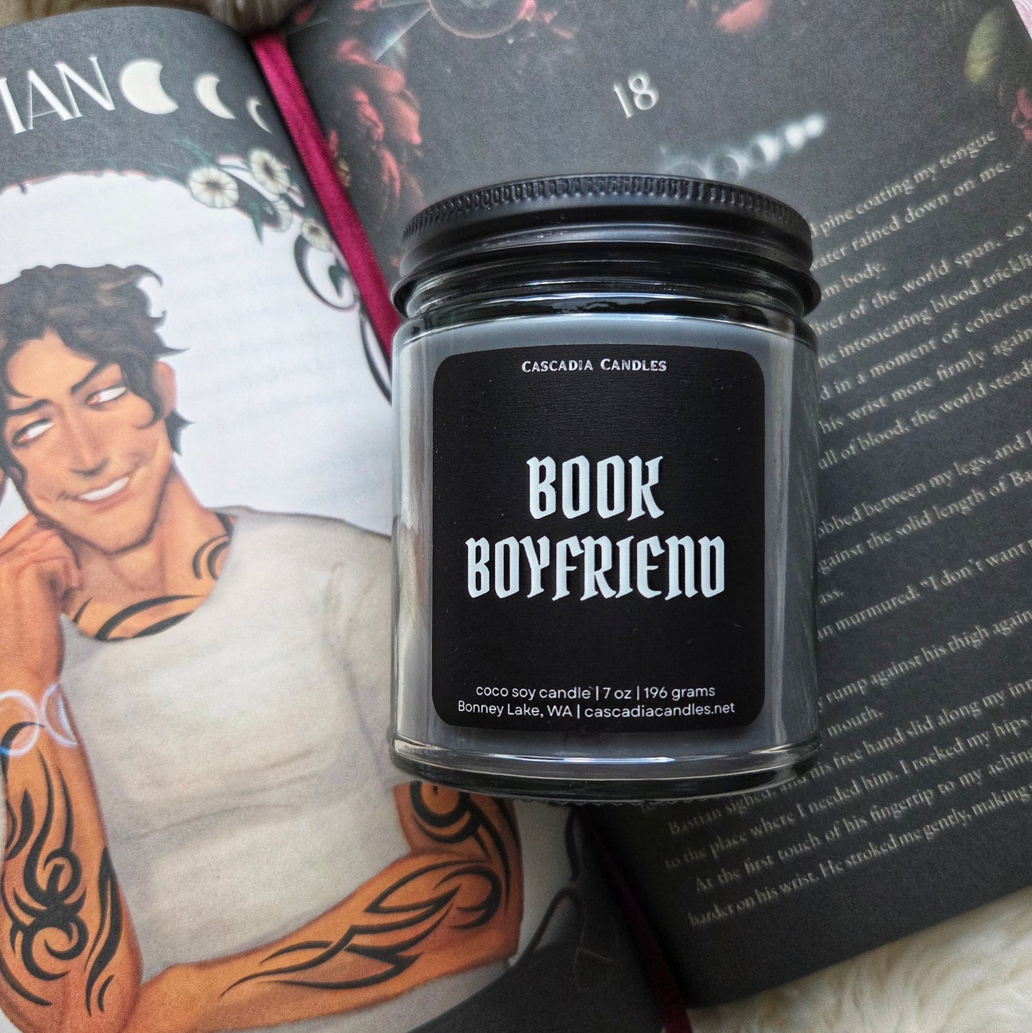 Candle jar labeled 'Book Boyfriend' on a book with a tattooed person featured.