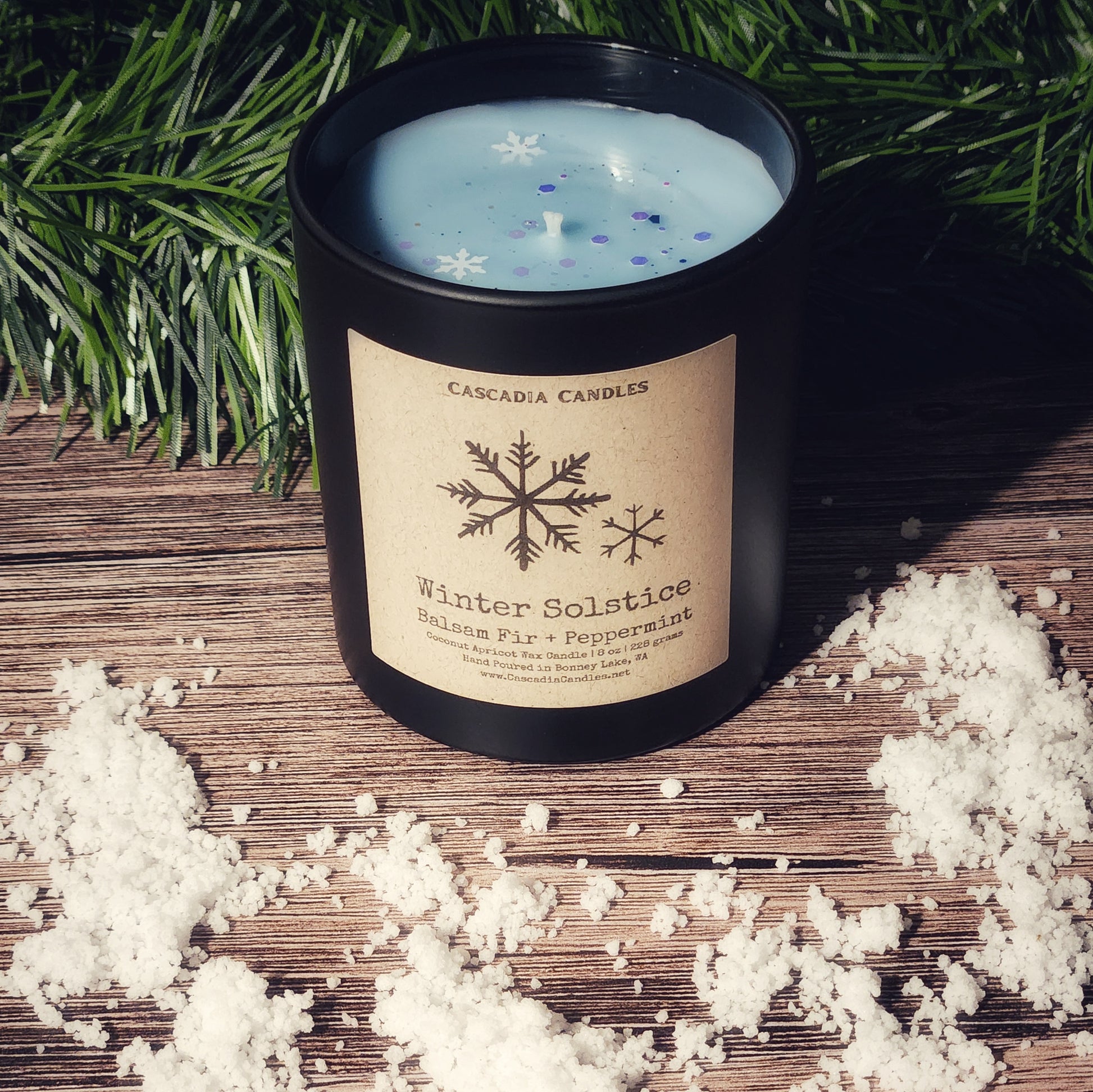 Candle labeled 'Winter Solstice' with decorative elements on a wooden surface.