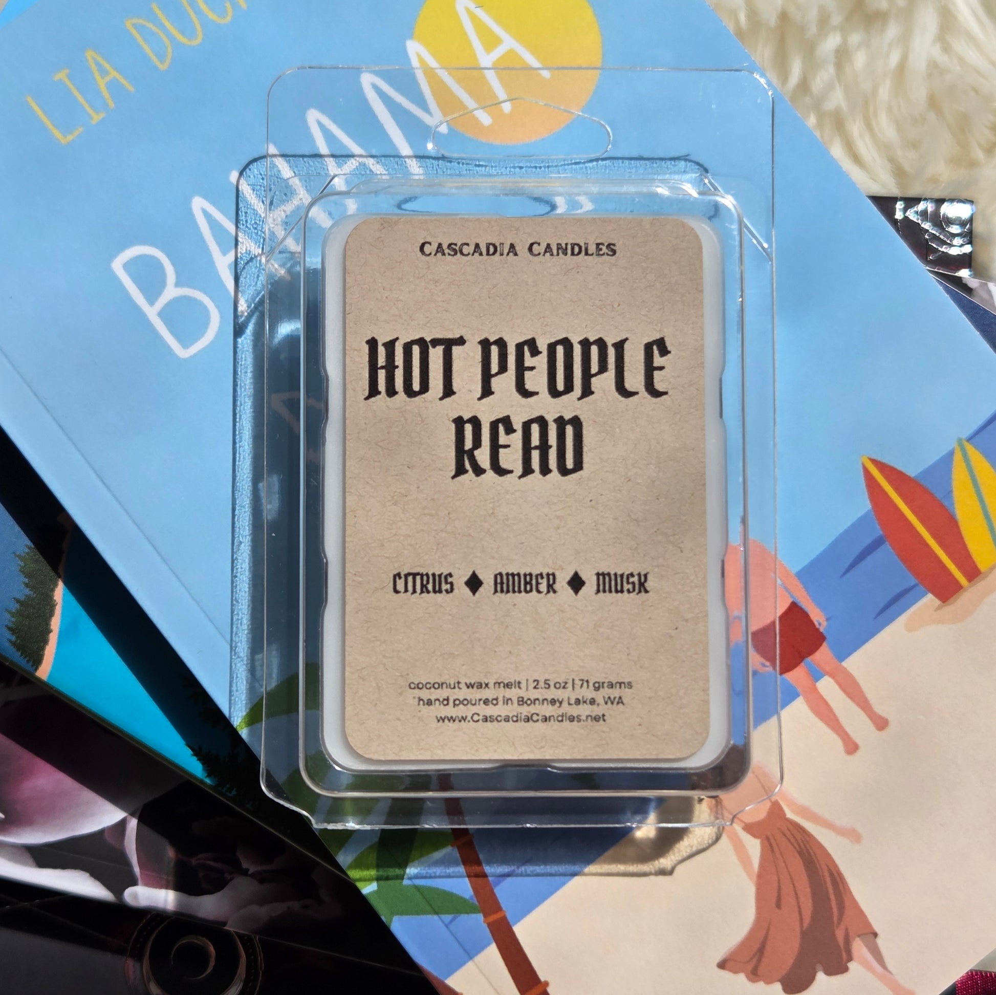 A single wax melt package from Cascadia Candles reading 'Hot People Read' with 'Citrus Amber Musk' scent, placed on top of colorful books.
