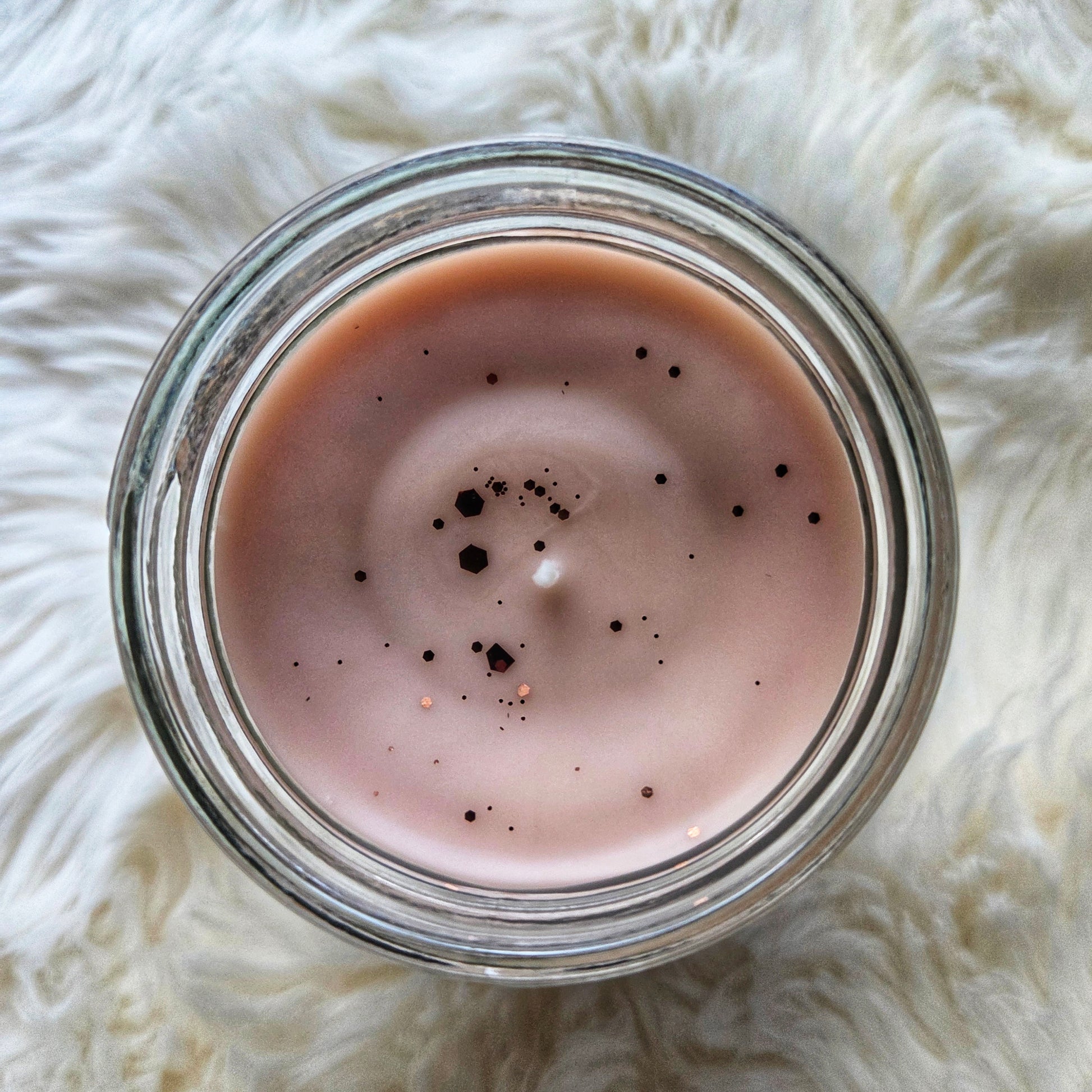 Top view of Witch's Brew candle on a white fluffy surface, showing the glitter on top.