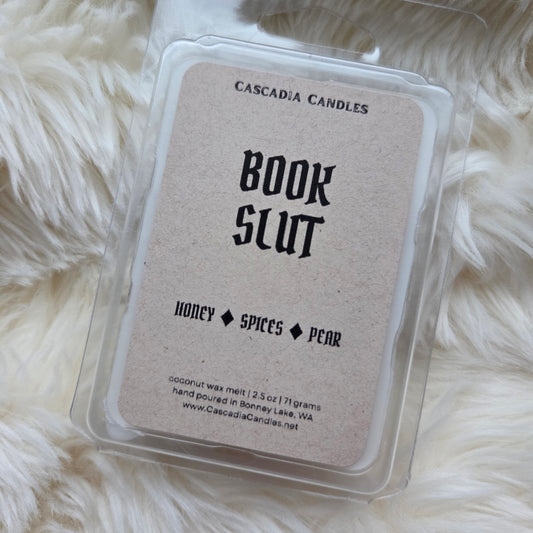 Wax melt package labeled 'Book Slut' by Cascadia Candles on a fluffy white surface.