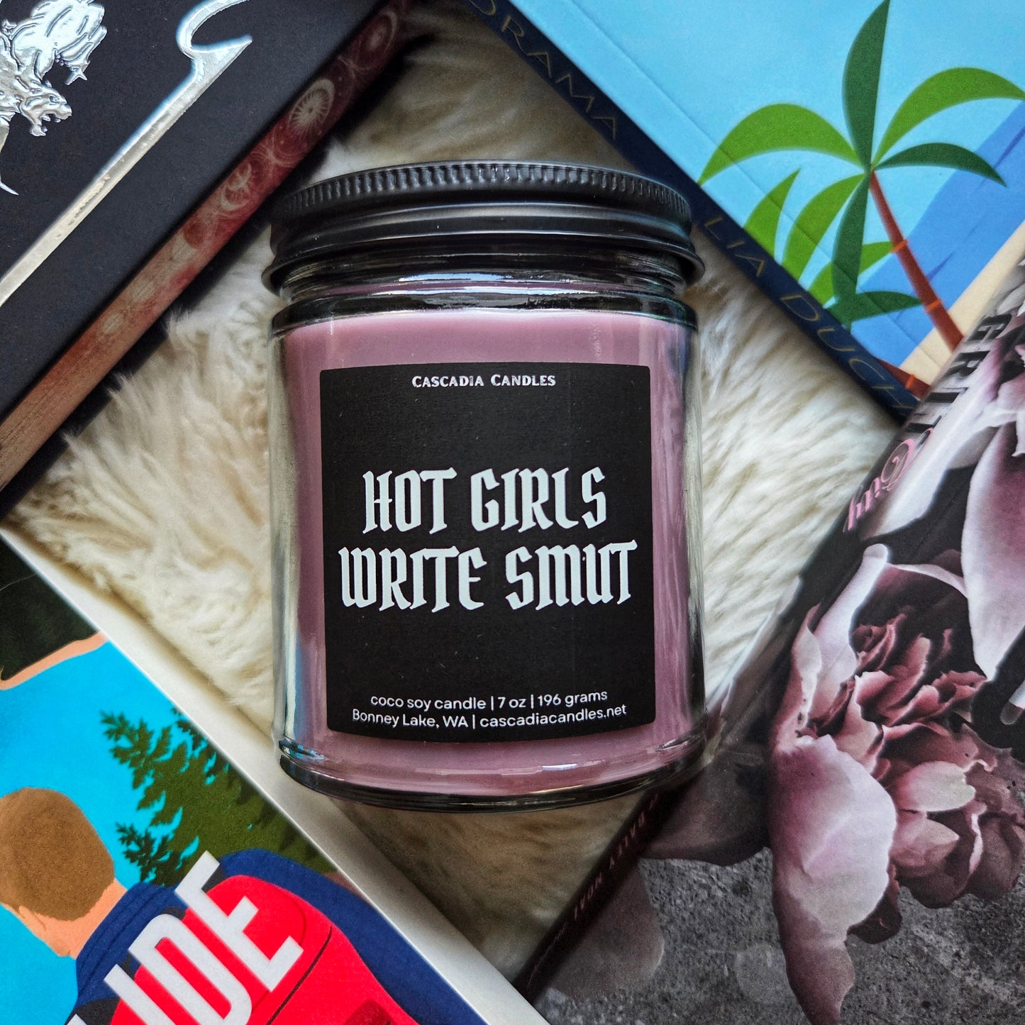 Candle with 'Hot Girls Write Smut' text on a textured surface
