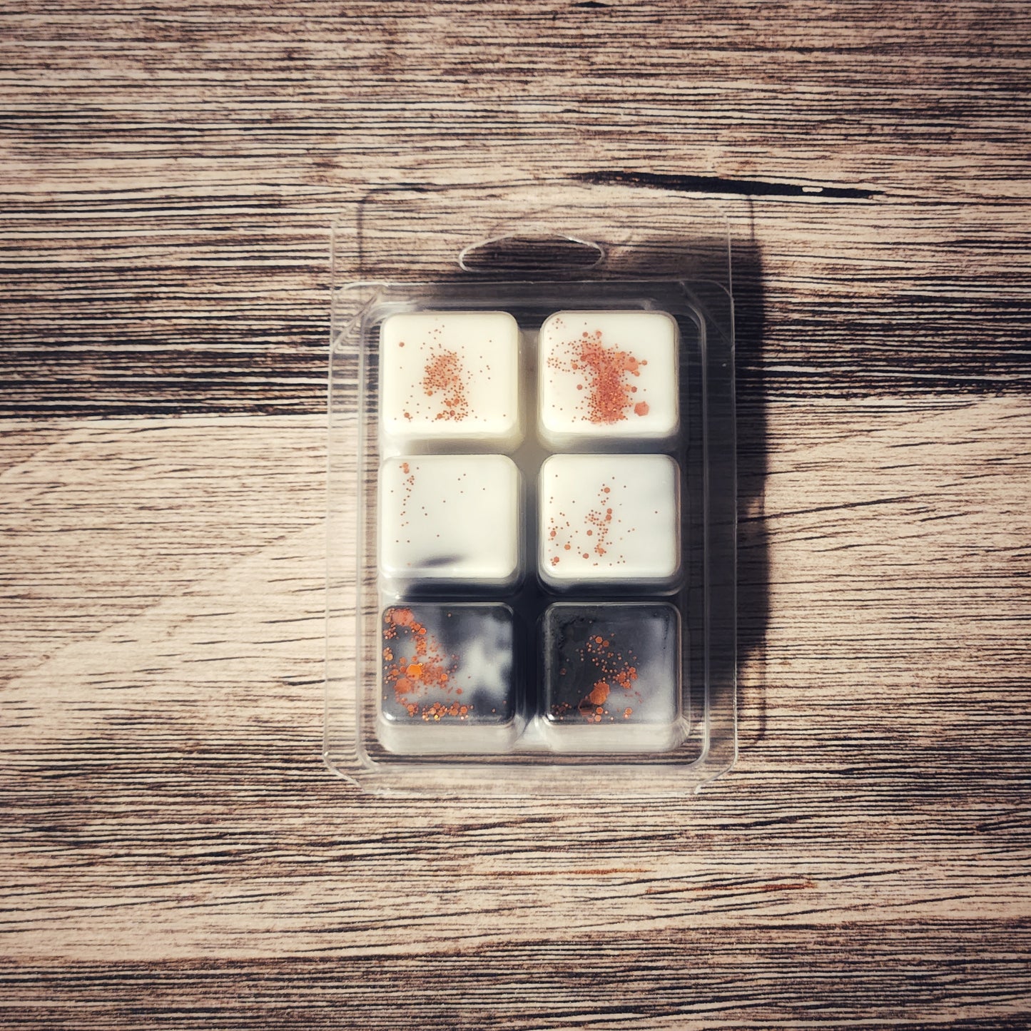 Packaged wax melts with glitter on a wooden surface