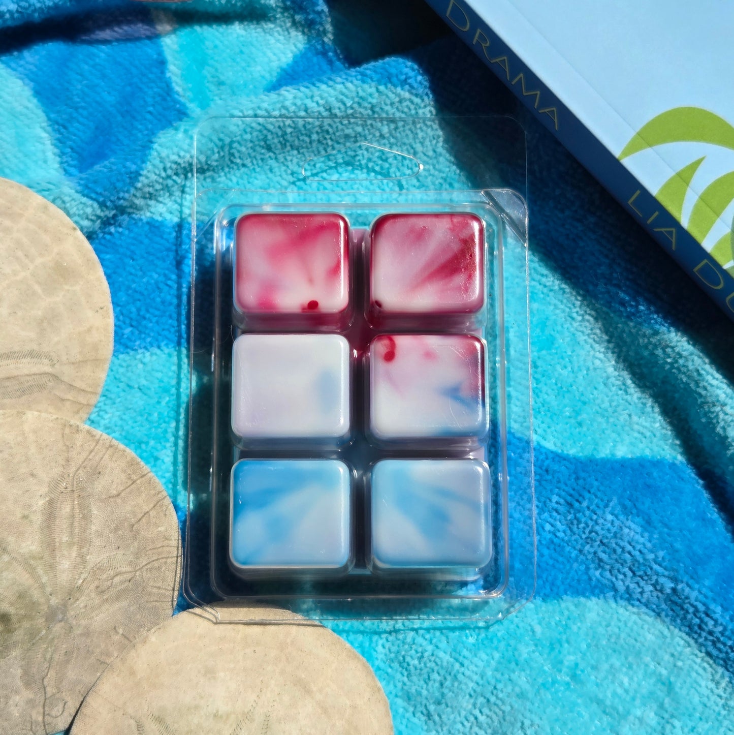Packaged wax melt cubes with red and blue marbled pattern on a blue towel