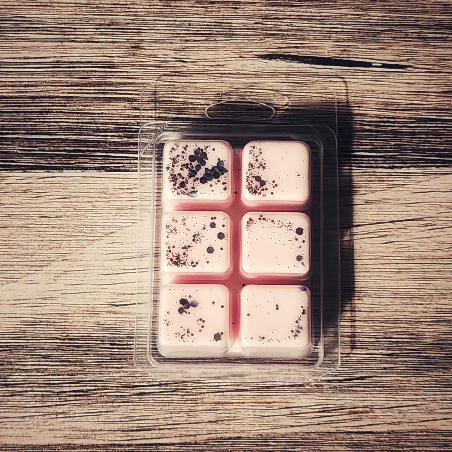 Packaged wax melts with speckled design on a wooden surface
