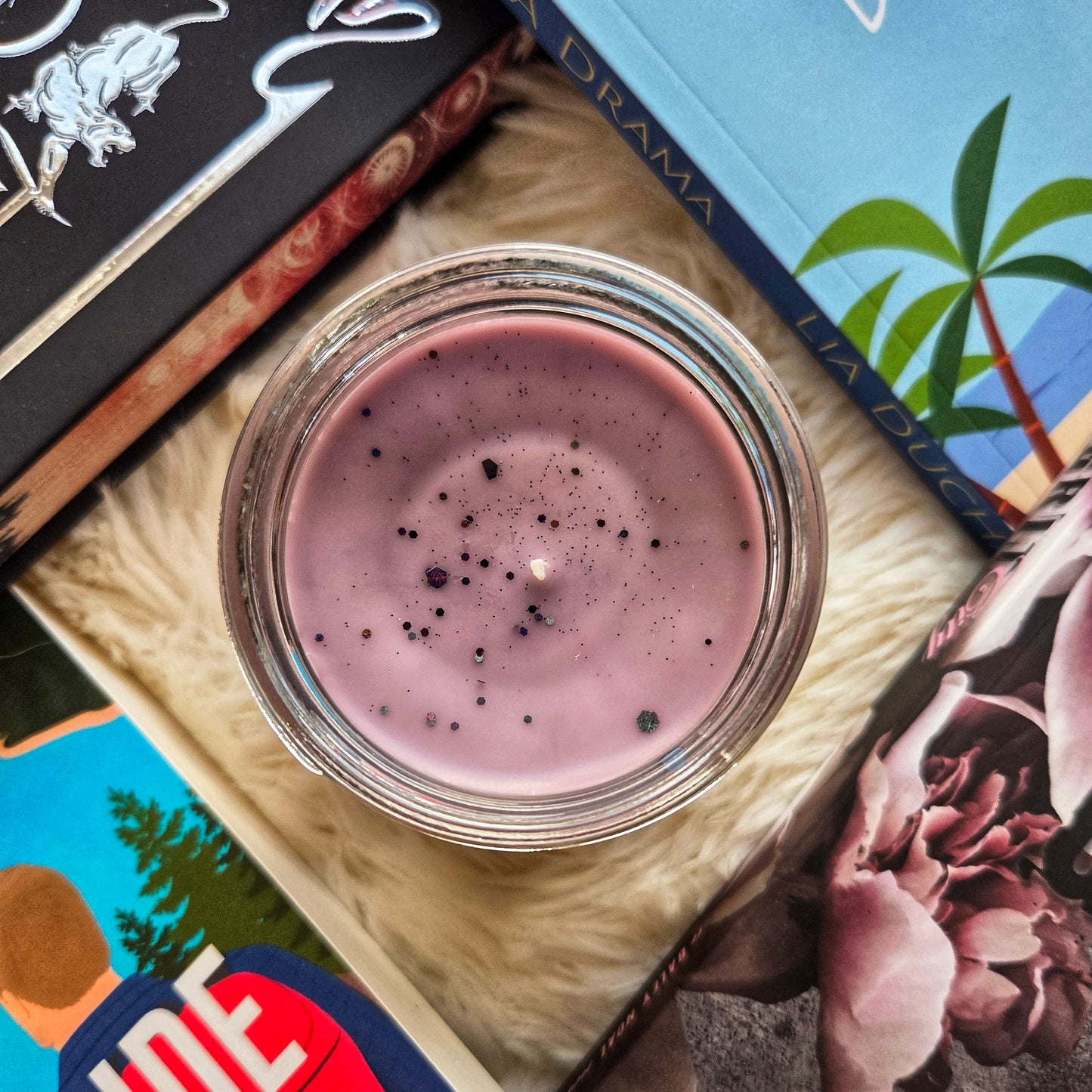 Jar of pink substance with books and a magazine on a textured surface