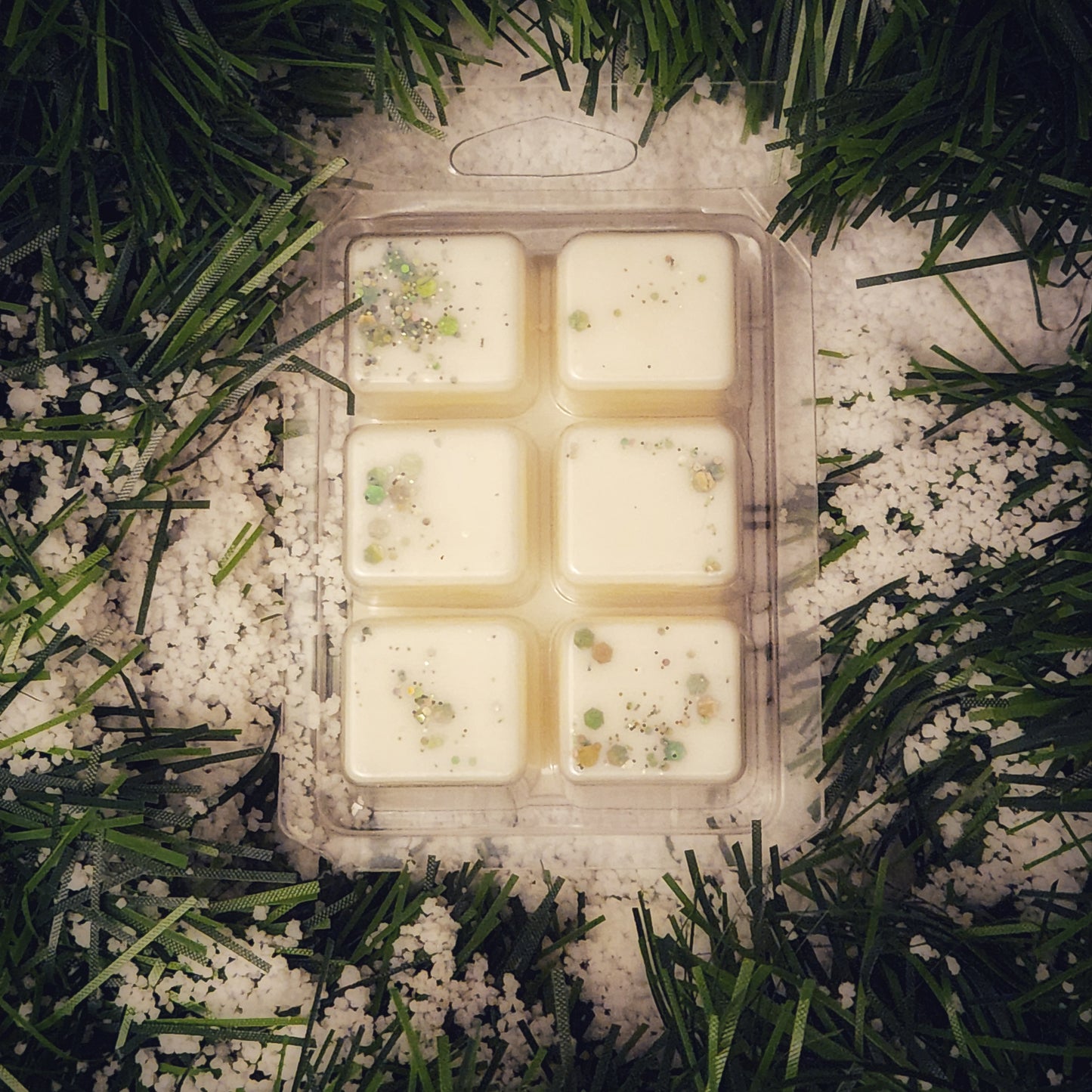 Packaged wax melts with decorative elements on a snowy grass background