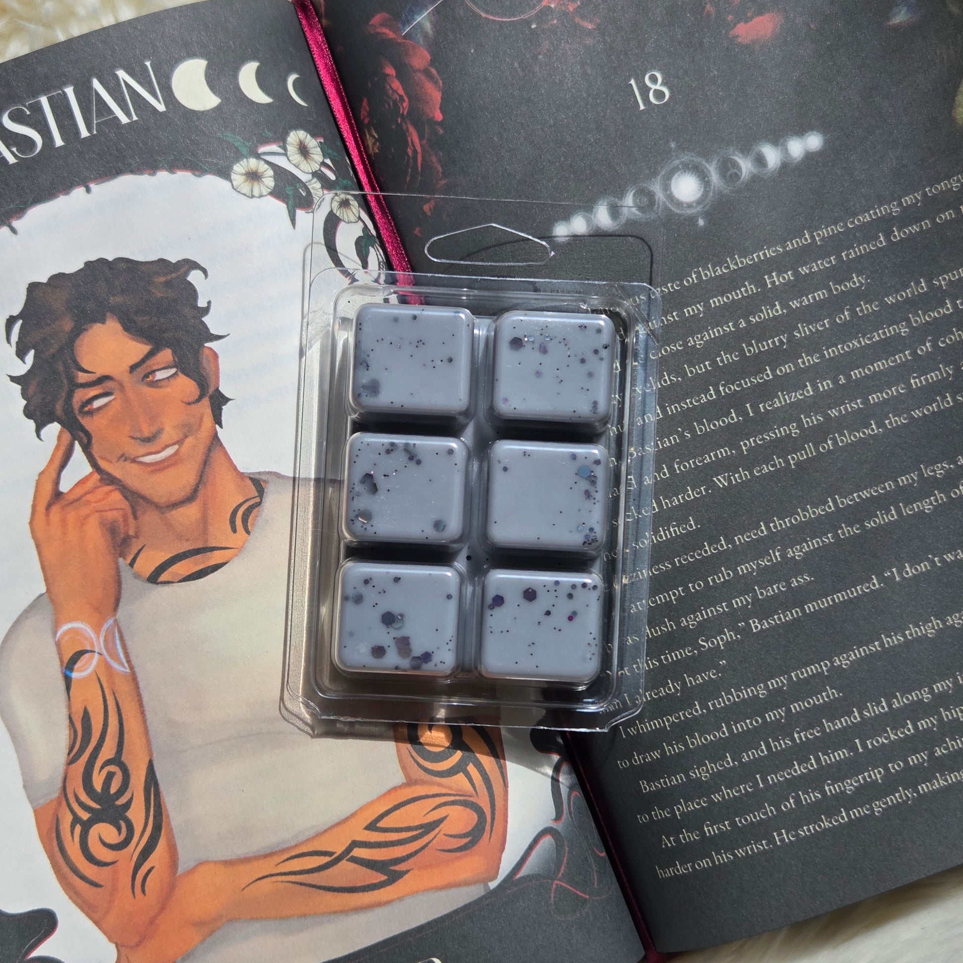 Six square wax melts in a clear plastic clamshell package, arranged in a 2x3 grid. The wax is a muted grayish purple with dark speckles.