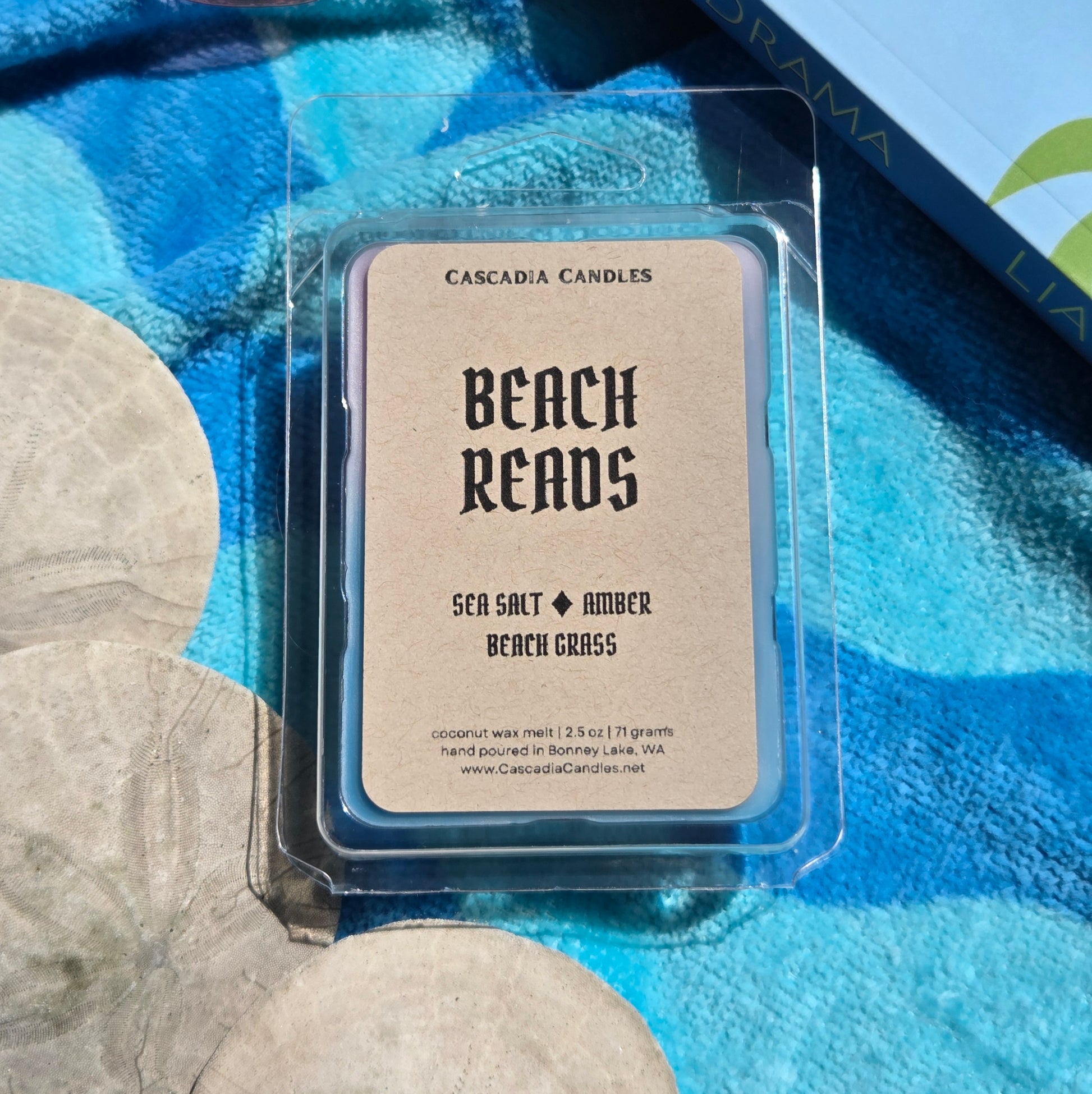 Wax melt package labeled 'Beach Reads' by Cascadia Candles on a blue fabric background.
